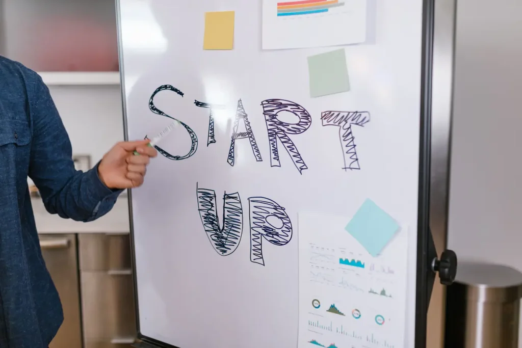 Personne debout devant tableau blanc avec mot START UP écrit, symbole des choix de financement entre Business Angel et Venture Capital pour une startup.