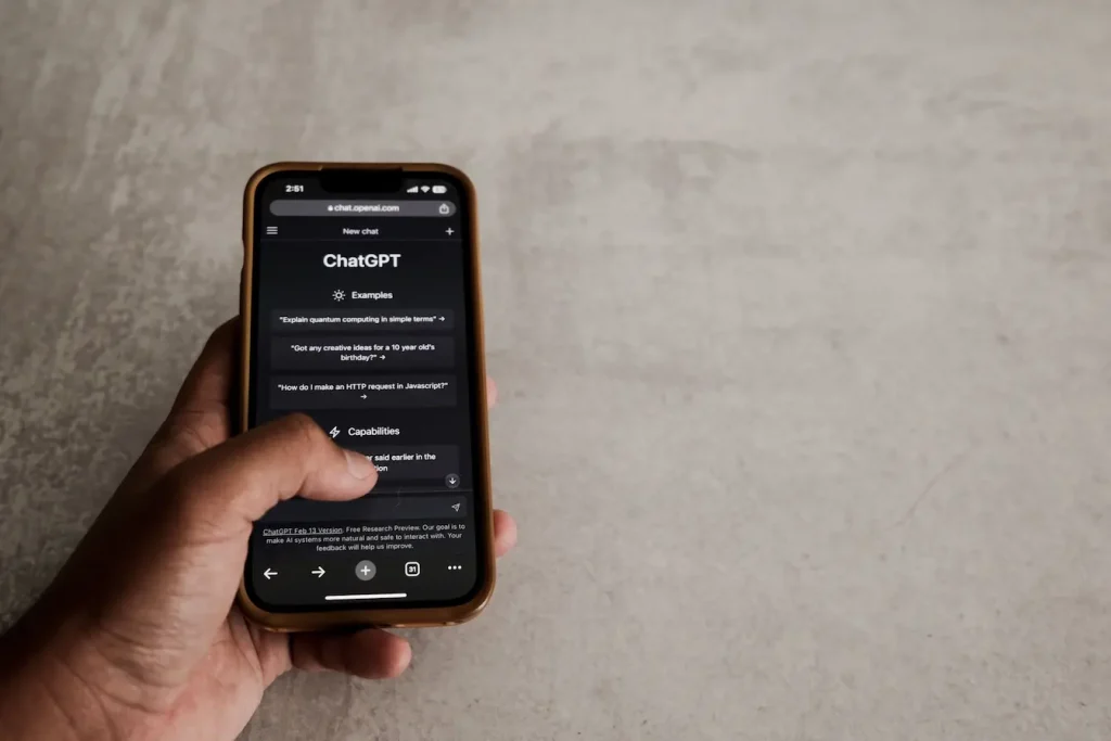 Main tenant un smartphone affichant l’interface ChatGPT, image qui illustre la recherche du prompt parfait pour ChatGPT.