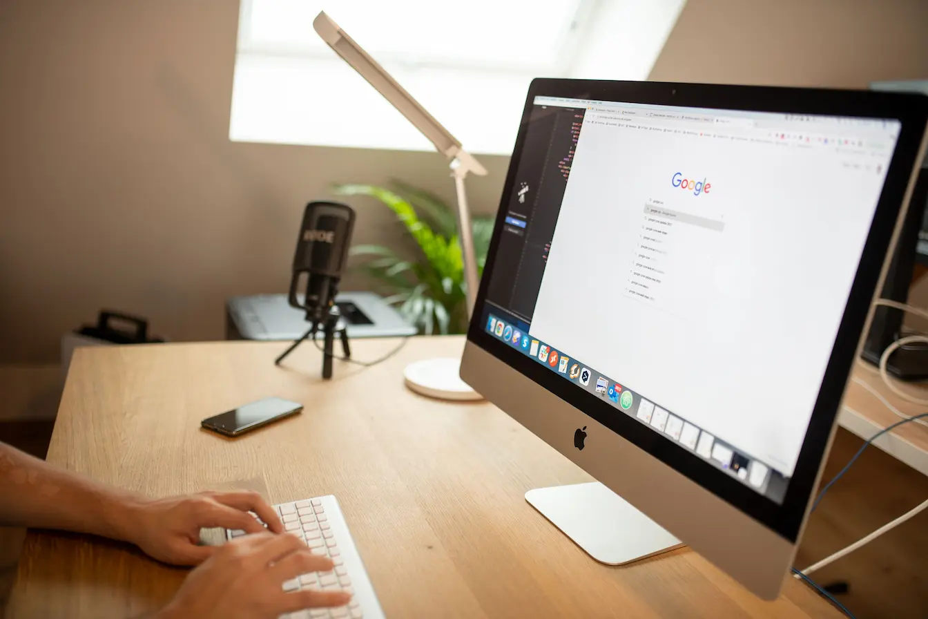 page Google Bureau moderne avec iMac affichant Google, image qui illustre la recherche vocale et SEO et l’adaptation de stratégie digitale.