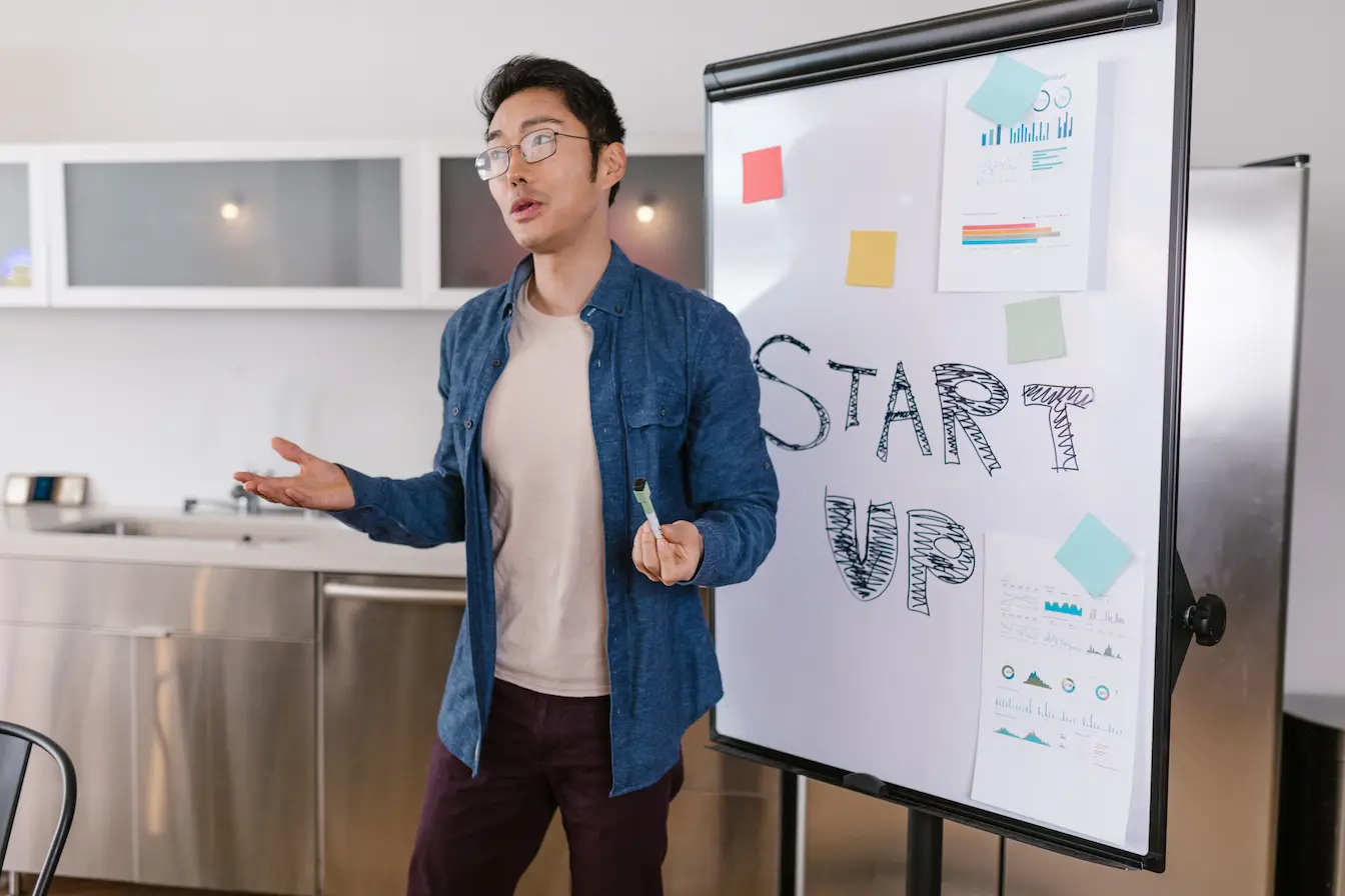 Personne debout devant tableau avec mot START UP écrit, symbole des démarches liées au choix du statut juridique d’une startup.