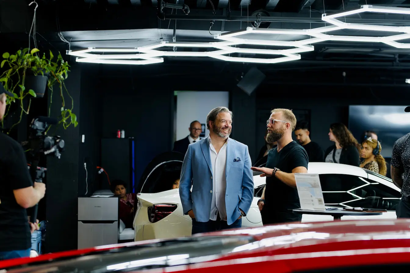 storytelling de marque Deux personnes échangent dans un showroom moderne avec voiture blanche, image qui illustre le storytelling de marque.