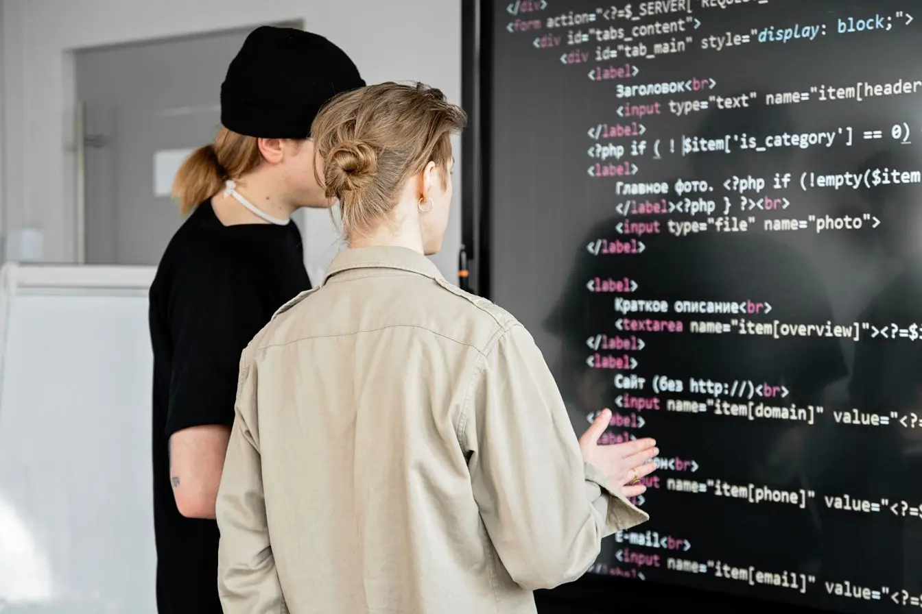 Serverless Deux développeurs analysent du code sur un grand écran, illustrant la simplicité du serverless pour créer des applications sans gérer de serveurs