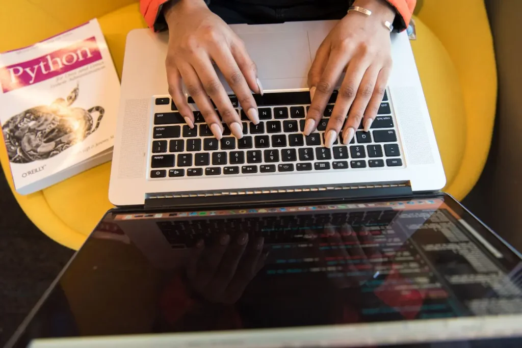 Personne tapant sur clavier avec écran affichant code, symbole du travail sur l’accessibilité web et la conformité RGAA.