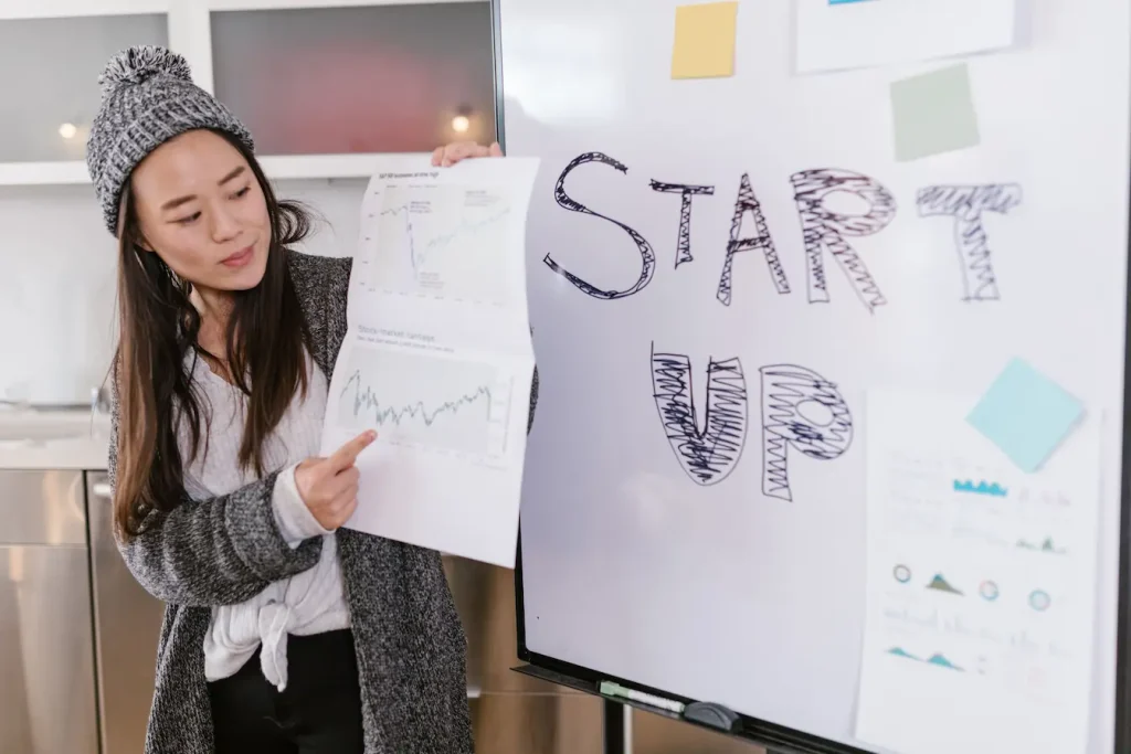 Personne présentant graphiques financiers devant tableau avec mention Start Up, symbole de la valorisation d’une jeune entreprise.