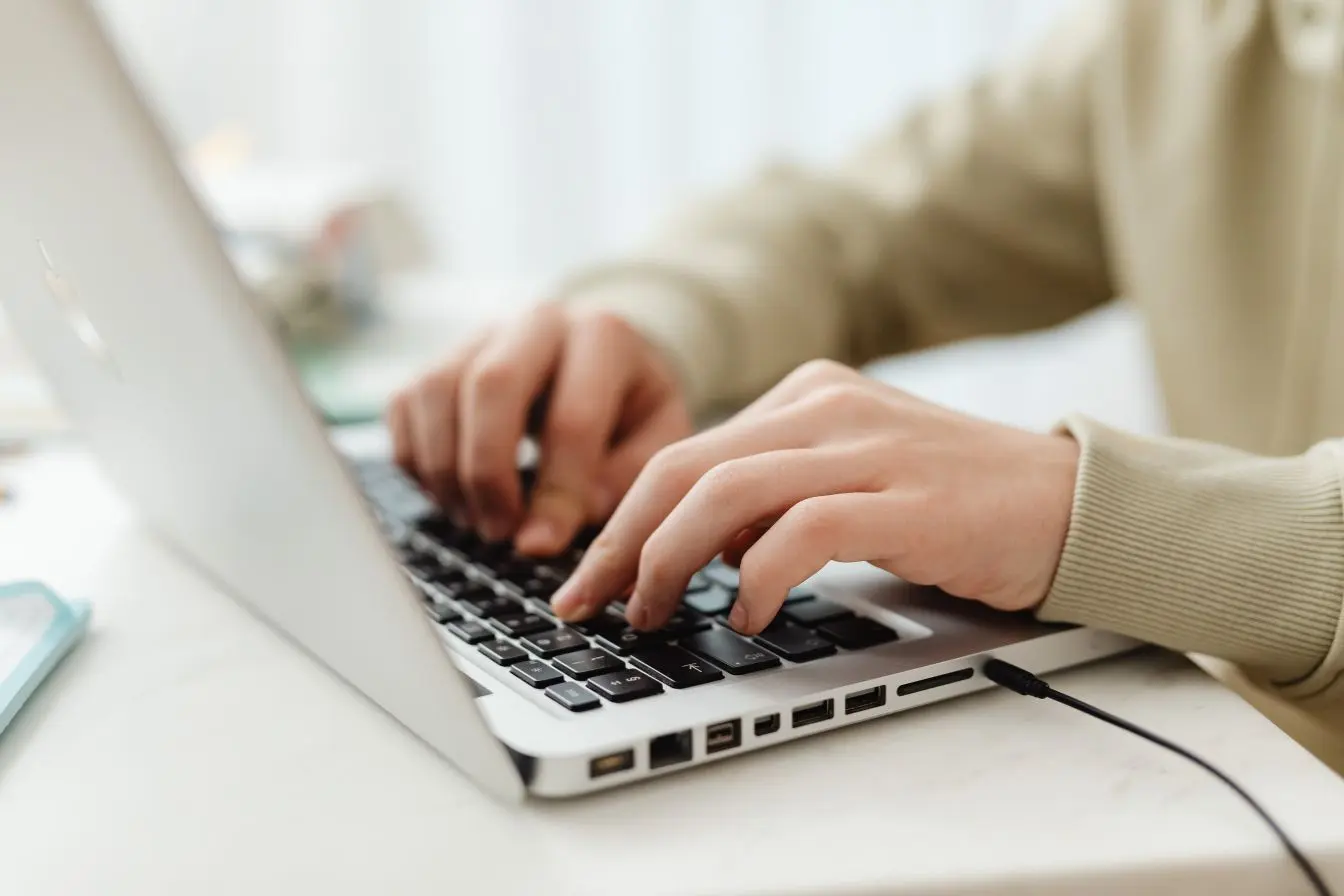 ordinateur portable Mains tapant sur un ordinateur portable dans un espace de travail épuré, illustrant le choix entre cloud public et cloud privé selon les besoins d’une organisation