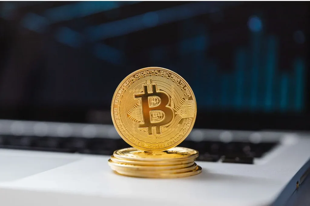 Une pile de pièces de bitcoin dorées posées sur un clavier d'ordinateur, illustrant l'univers de la cryptomonnaie et des NFT.
