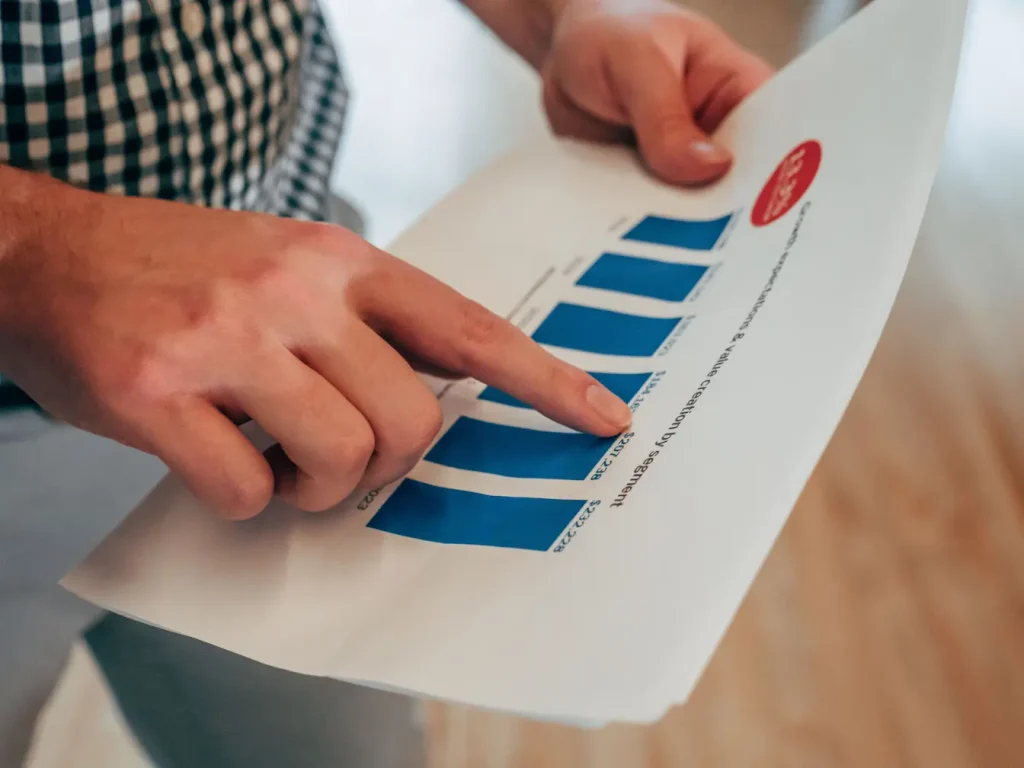 Personne en chemise à carreaux tenant graphique à barres bleues, symbole de l’analyse du churn rate SaaS.